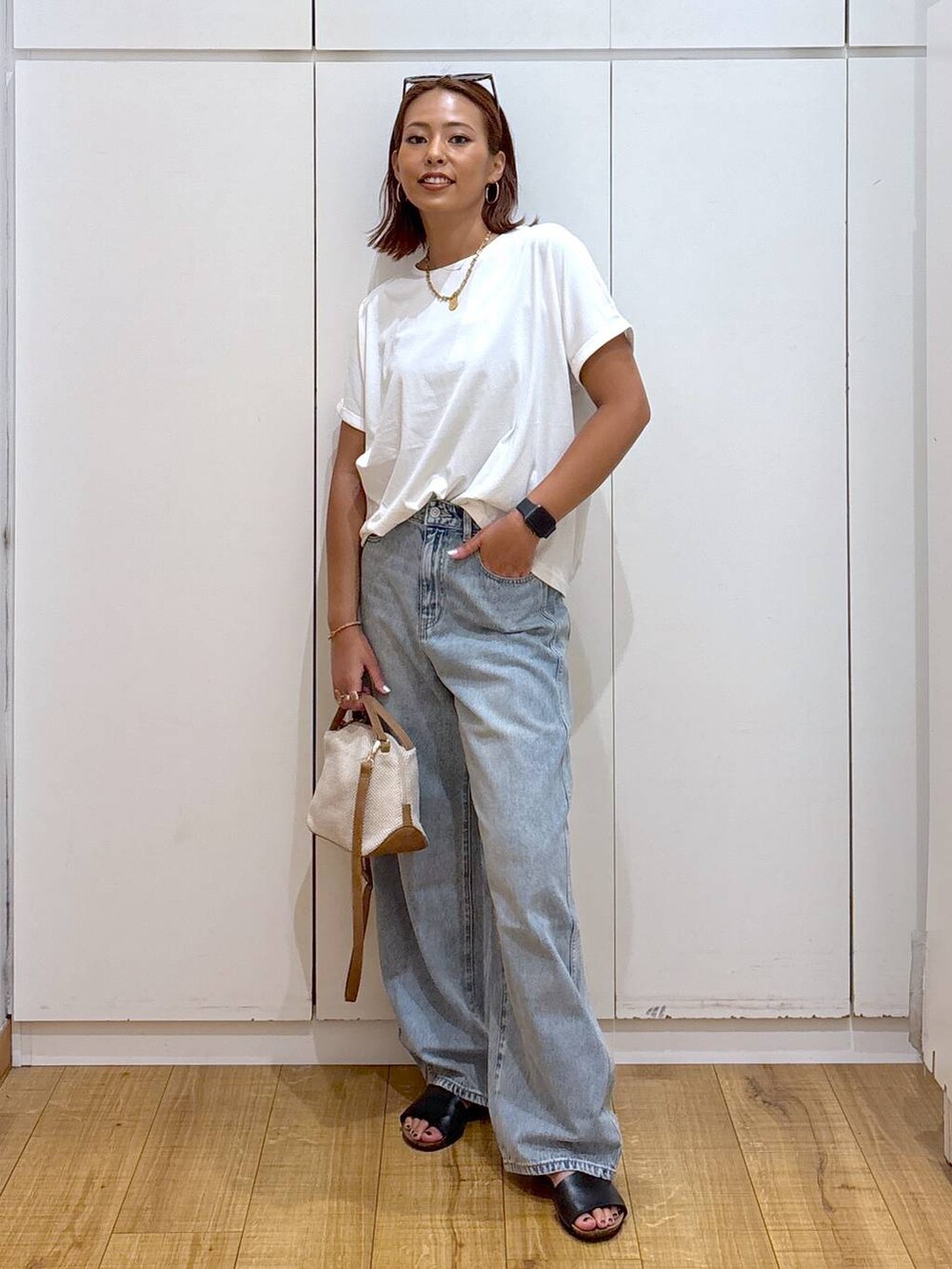 ブルー系のデニムパンツ、ホワイト系のショルダーバッグ、ホワイト系のTシャツ/カットソーを着用したレディースの夏コーディネートの2枚目の写真