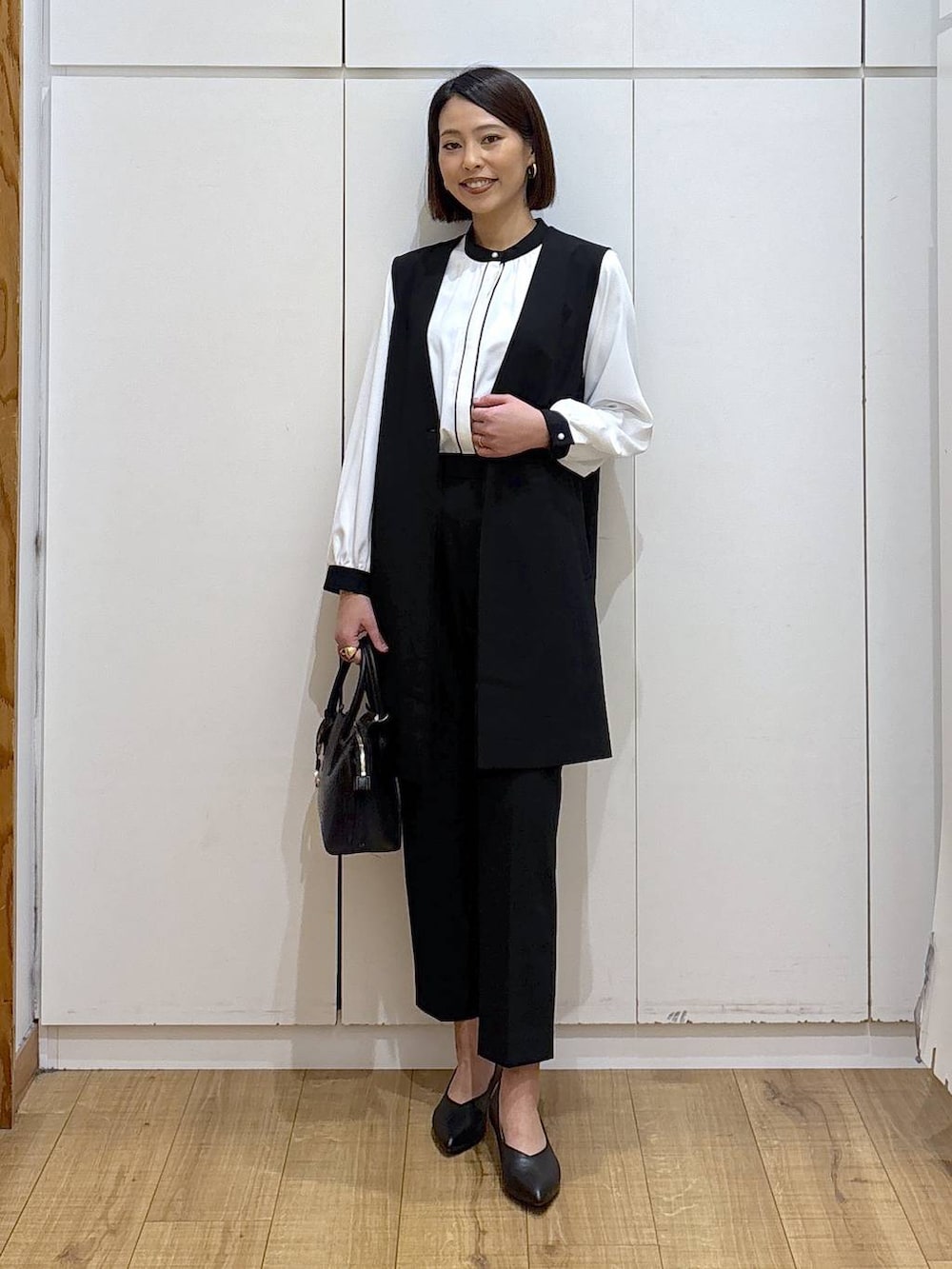 ブラック系のショルダーバッグ、ブラック系のパンプス、ブラック系のスラックスを着用したレディースの冬コーディネートの8枚目の写真