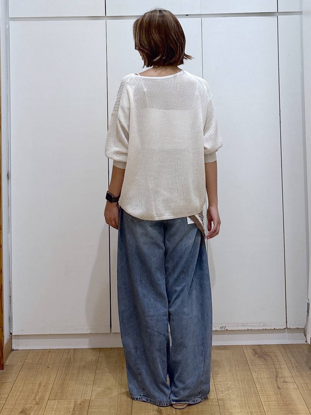 ホワイト系のキャミソール、ブルー系のデニムパンツ、ホワイト系のニット/セーターを着用したレディースの春コーディネートの5枚目の写真