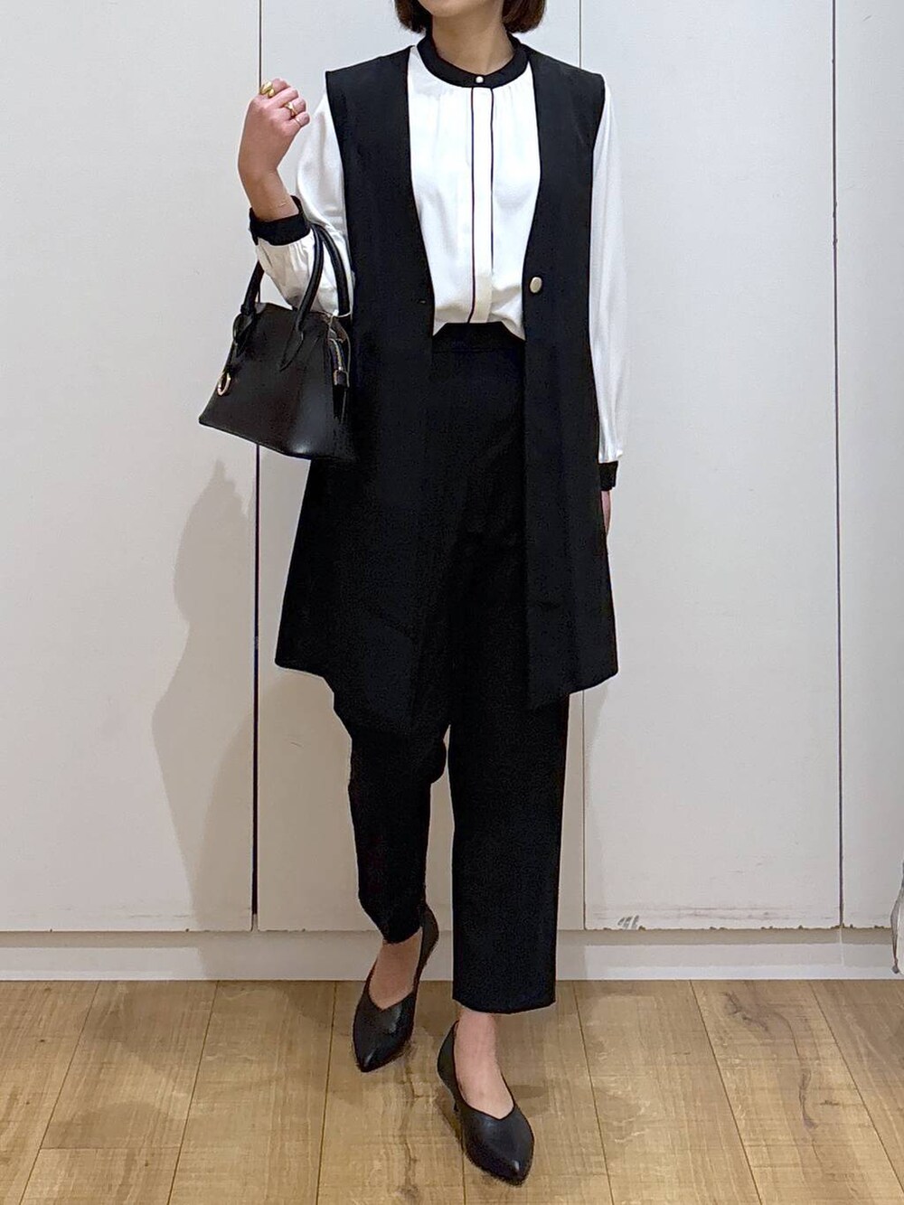 ブラック系のショルダーバッグ、ブラック系のパンプス、ブラック系のスラックスを着用したレディースの冬コーディネートの4枚目の写真