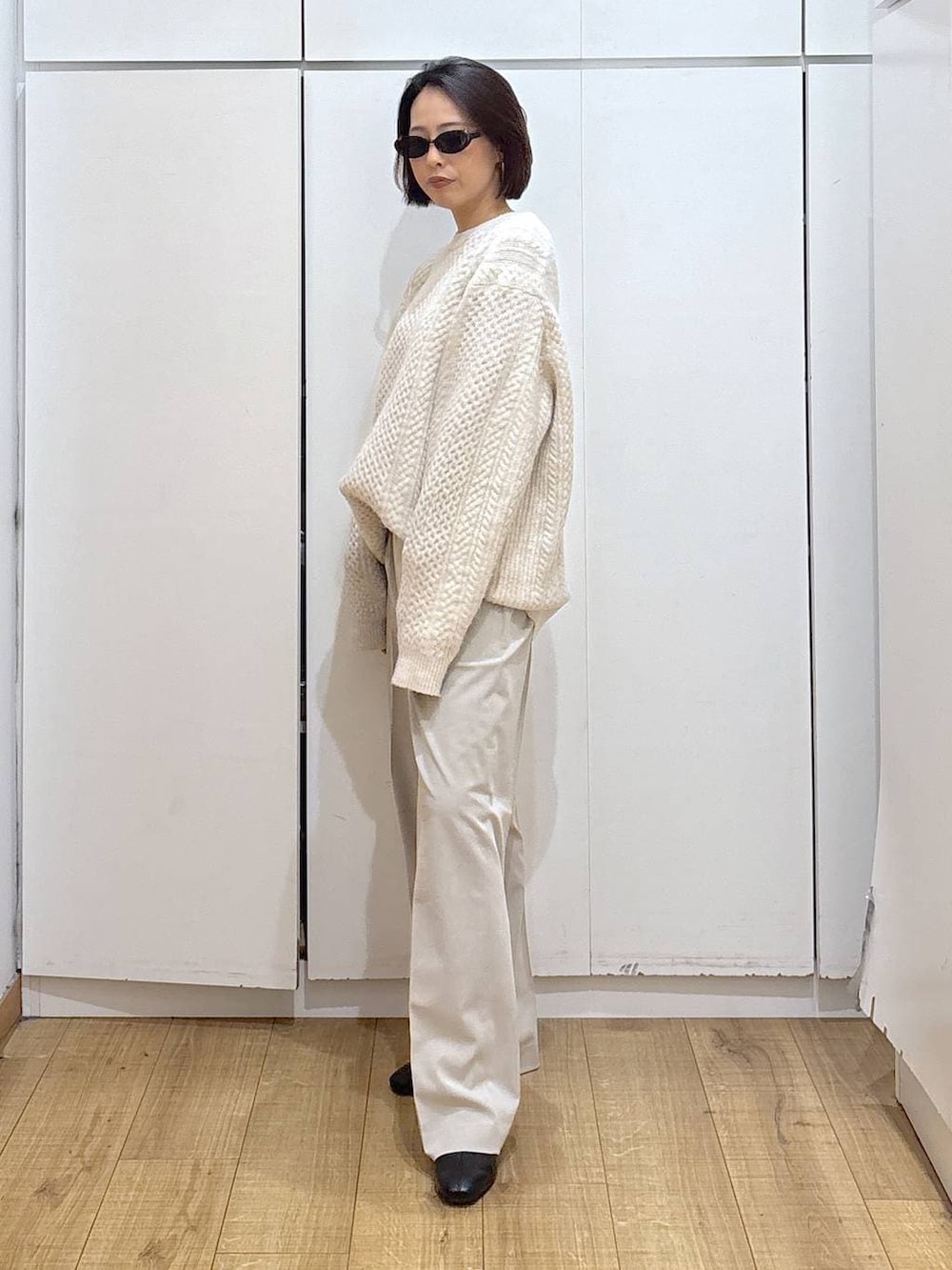 ベージュ系のスラックス、ブラック系のブーツ、ホワイト系のニット/セーターを着用したレディースの冬コーディネートの3枚目の写真