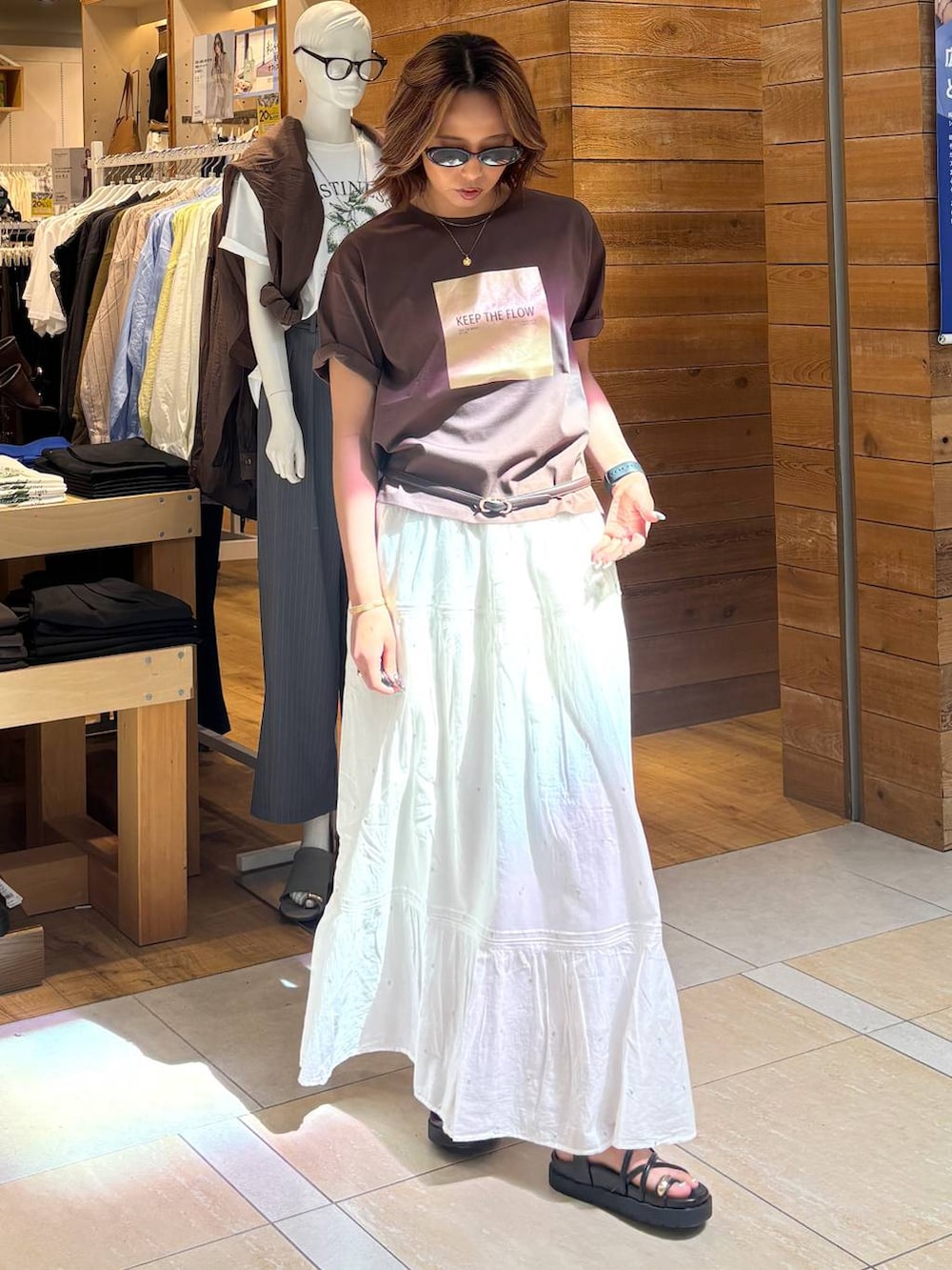 ホワイト系のスカート、ブラウン系のTシャツ/カットソー、ブラック系のサンダルを着用したレディースの春コーディネートの5枚目の写真