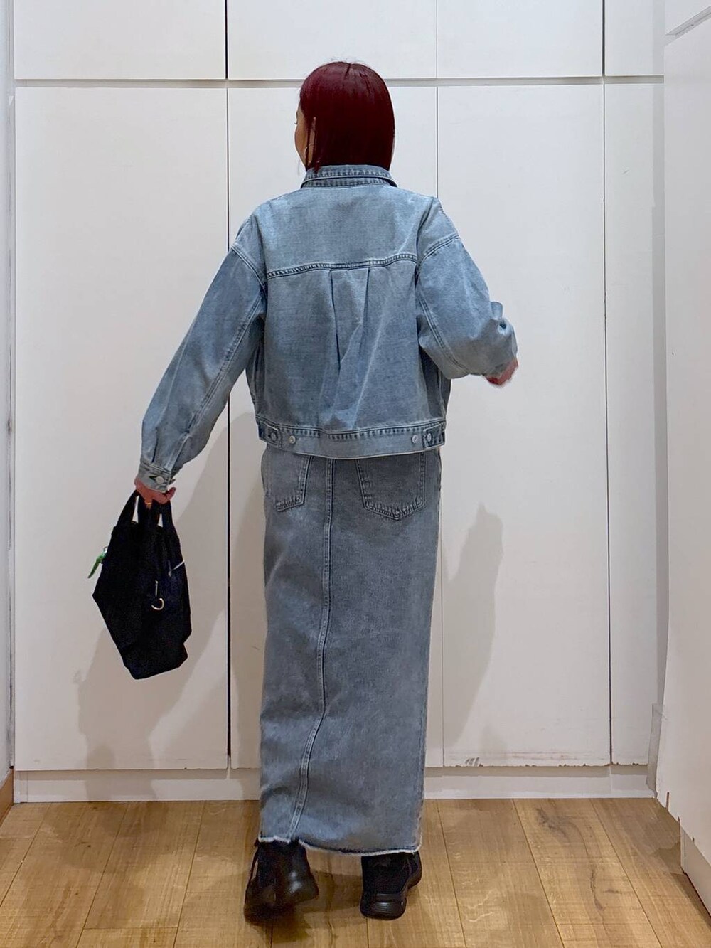 ブルー系のスカート、ブルー系のデニムジャケット、ブラック系のスニーカーを着用したレディースの春コーディネートの4枚目の写真