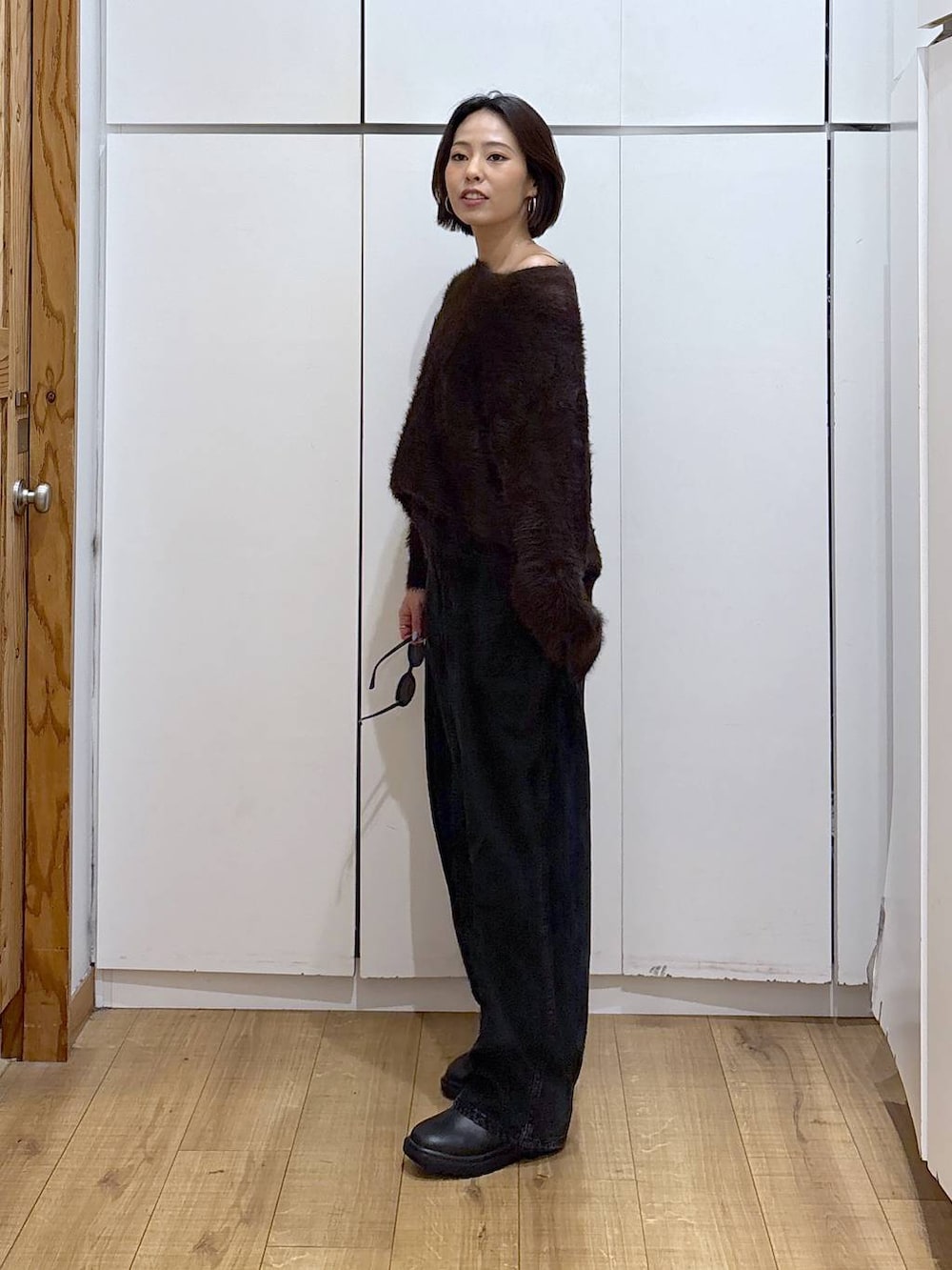 ブラック系のデニムパンツ、ブラック系のブーツ、ブラウン系のニット/セーターを着用したレディースの冬コーディネートの4枚目の写真