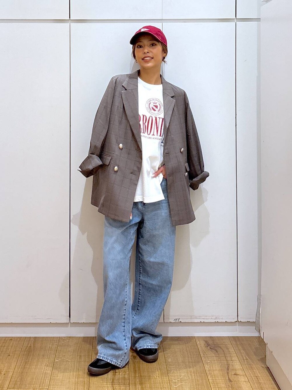 ブラック系のスニーカー、ブラウン系のテーラードジャケット、ブルー系のデニムパンツを着用したレディースの秋コーディネートの3枚目の写真