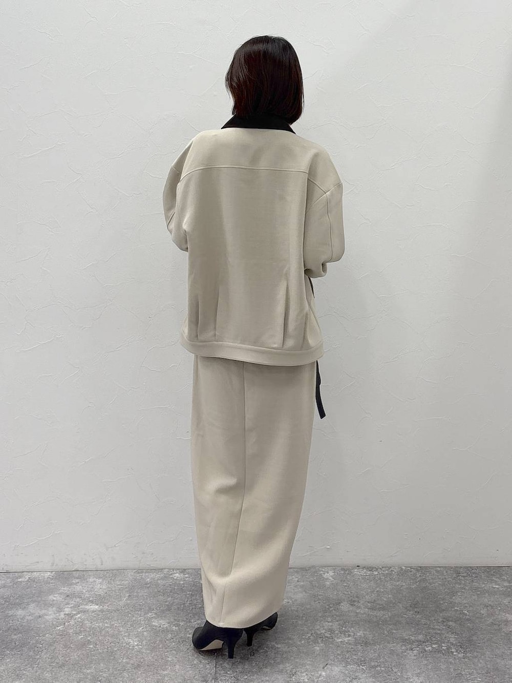 ブラック系のブーツ、ブラック系のショルダーバッグ、ベージュ系のスカートを着用したレディースの冬コーディネートの5枚目の写真