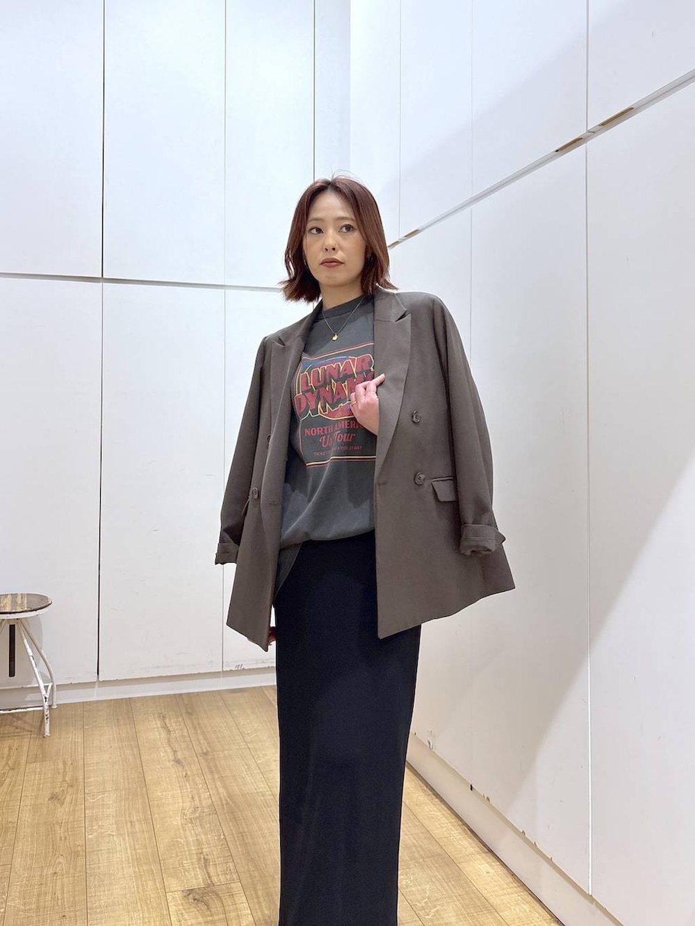 ブラウン系のテーラードジャケット、ブラック系のスカート、ゴールド系のネックレスを着用したレディースの春コーディネートの4枚目の写真