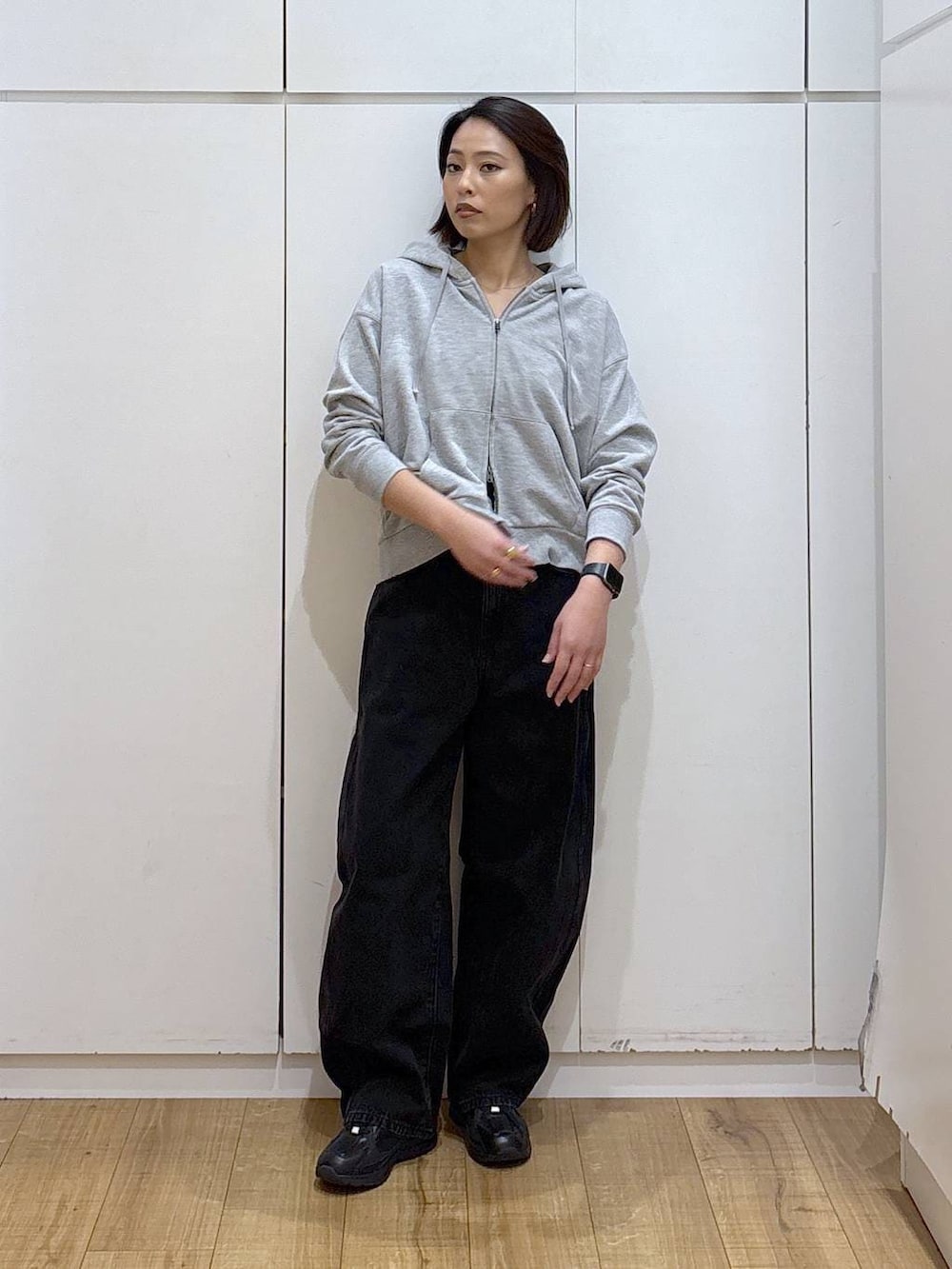 ブラック系のスニーカー、ブラック系のデニムパンツ、グレー系のパーカーを着用したレディースの冬コーディネートの2枚目の写真