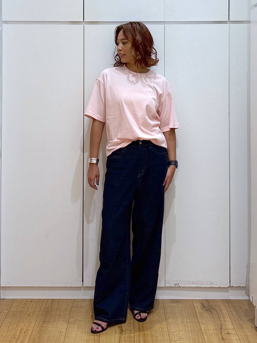 ブルー系のデニムパンツ、ピンク系のTシャツ/カットソー、ブラック系のサンダルを着用したレディースの夏コーディネートの2枚目の写真