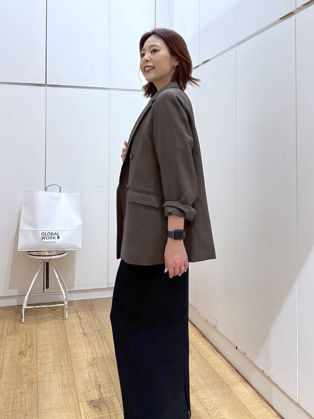 ブラウン系のテーラードジャケット、ブラック系のスカート、ゴールド系のネックレスを着用したレディースの春コーディネートの5枚目の写真