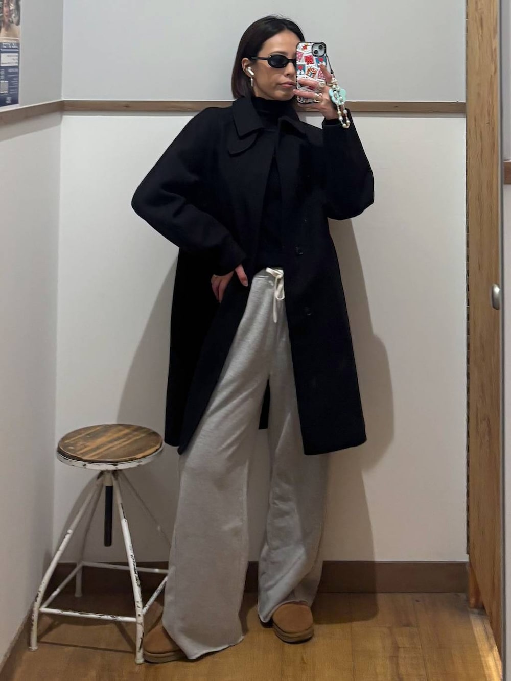 ブラック系のステンカラーコート、ブラック系のニット/セーター、グレー系のスウェットパンツを着用したレディースの冬コーディネートの4枚目の写真