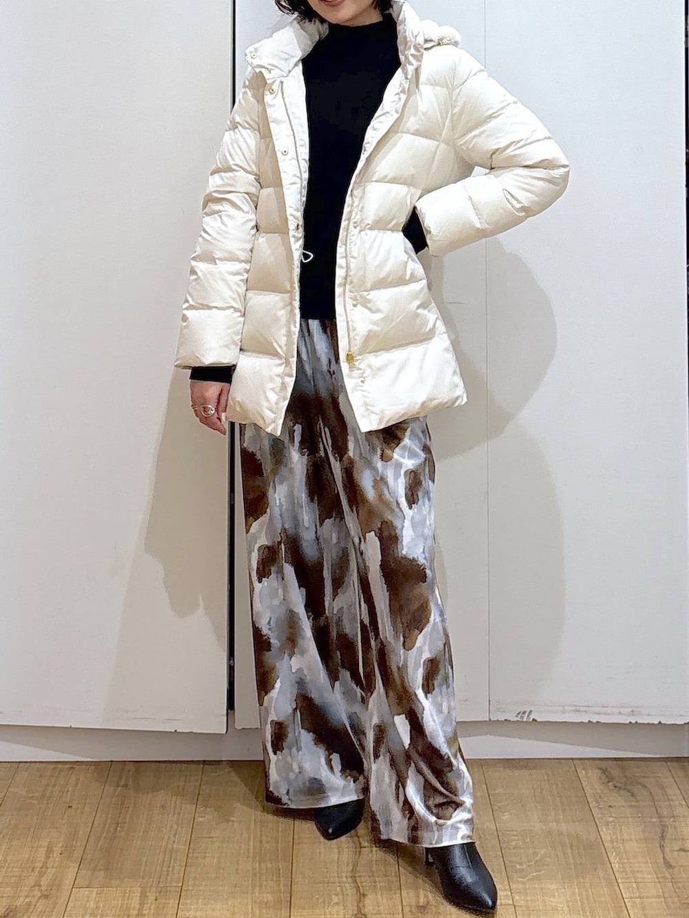 ベージュ系のダウンジャケット/コート、ブラック系のニット/セーター、ブラック系のブーツを着用したレディースの冬コーディネートの2枚目の写真