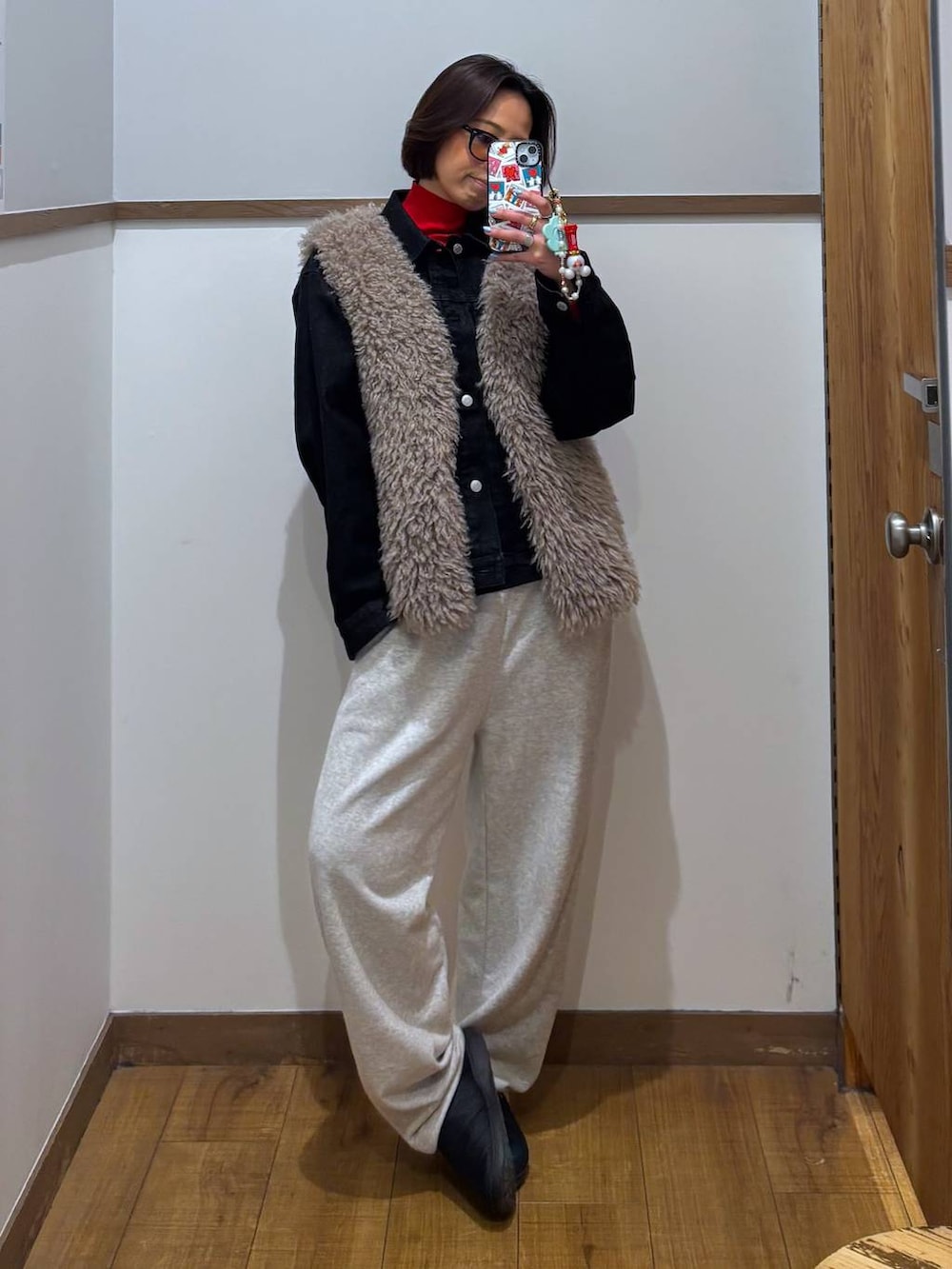 レッド系のニット/セーター、ブラック系のデニムジャケット、ゴールド系のピアス(両耳用)を着用したレディースの冬コーディネートの2枚目の写真