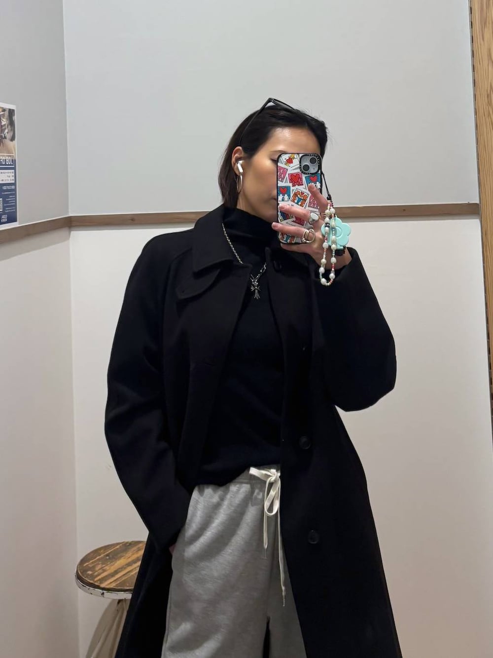 ブラック系のステンカラーコート、ブラック系のニット/セーター、グレー系のスウェットパンツを着用したレディースの冬コーディネートの5枚目の写真