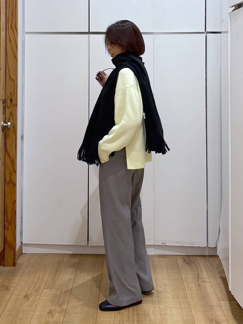 イエロー系のニット/セーター、グレー系のその他パンツ、ブラック系のショルダーバッグを着用したレディースの冬コーディネートの7枚目の写真