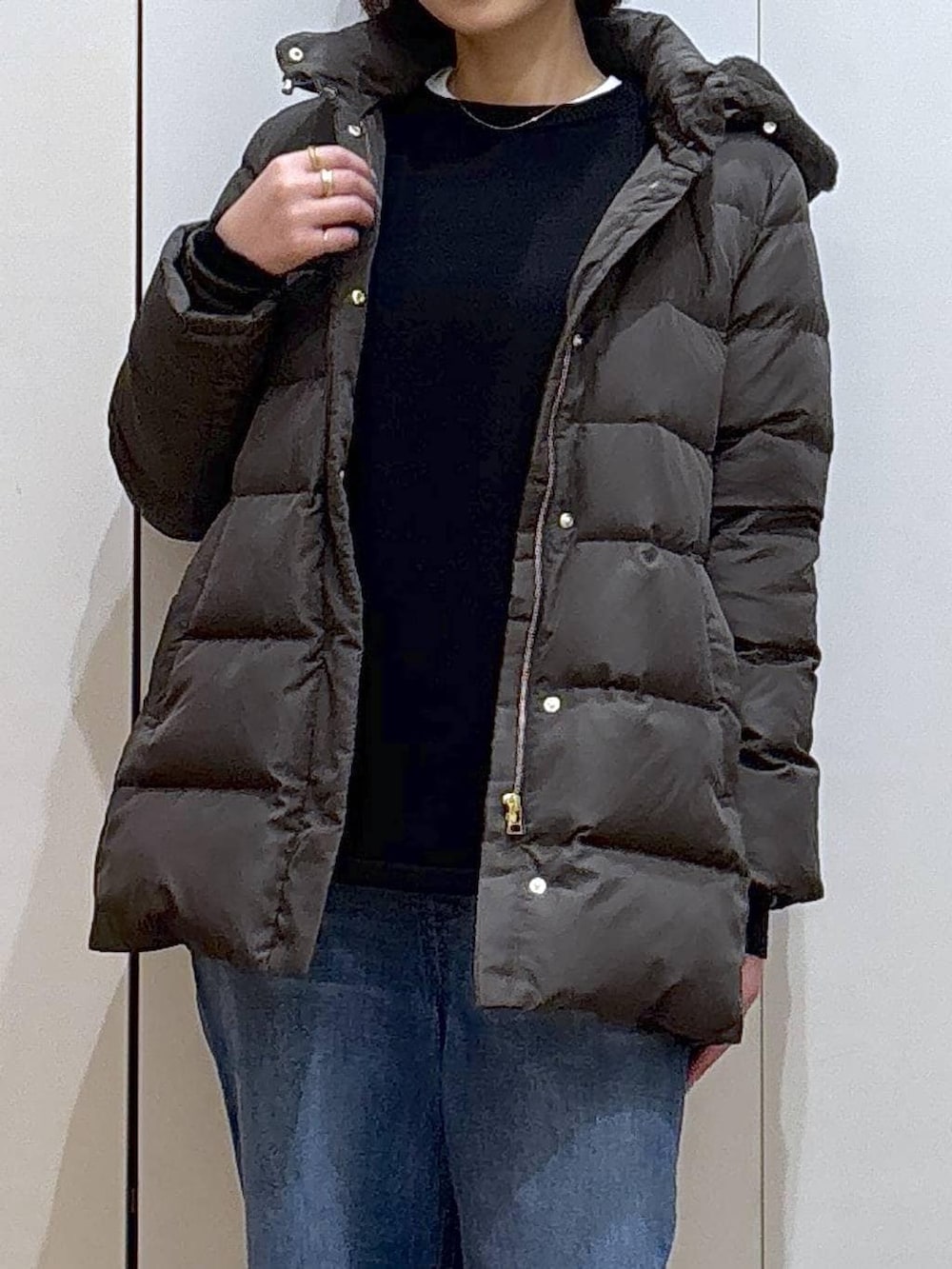 ブラック系のニット/セーター、ブラウン系のダウンジャケット/コート、ホワイト系のTシャツ/カットソーを着用したレディースの冬コーディネートの2枚目の写真