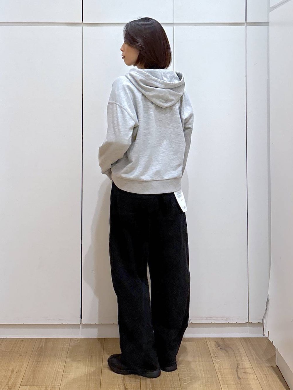 ブラック系のスニーカー、ブラック系のデニムパンツ、グレー系のパーカーを着用したレディースの冬コーディネートの4枚目の写真