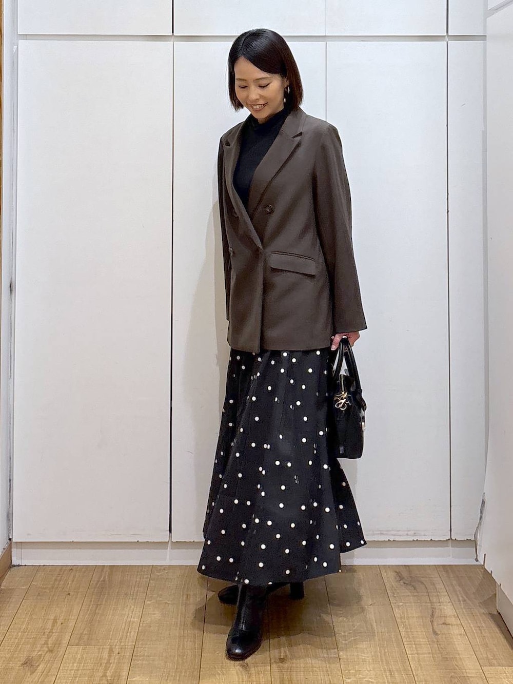 ブラック系のショルダーバッグ、ブラック系のTシャツ/カットソー、ブラック系のブーツを着用したレディースの冬コーディネートの5枚目の写真