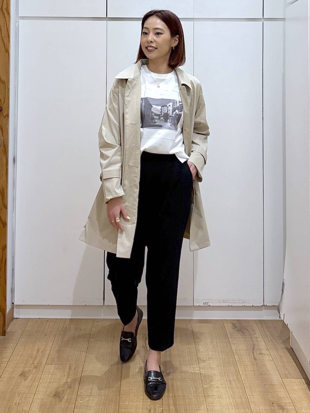 ブラック系のローファー、ブラック系のスラックス、ベージュ系のステンカラーコートを着用したレディースの春コーディネートの2枚目の写真