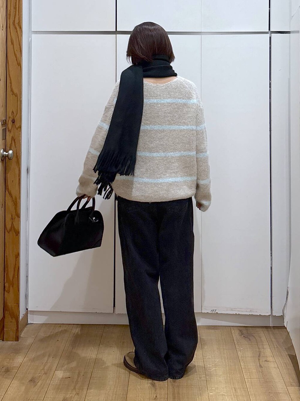 ブラック系のデニムパンツ、ベージュ系のローファー、ブラック系のショルダーバッグを着用したレディースの冬コーディネートの2枚目の写真