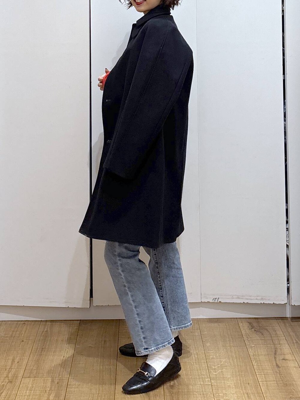 ブラック系のローファー、ブラック系のステンカラーコート、ブルー系のデニムパンツを着用したレディースの冬コーディネートの3枚目の写真