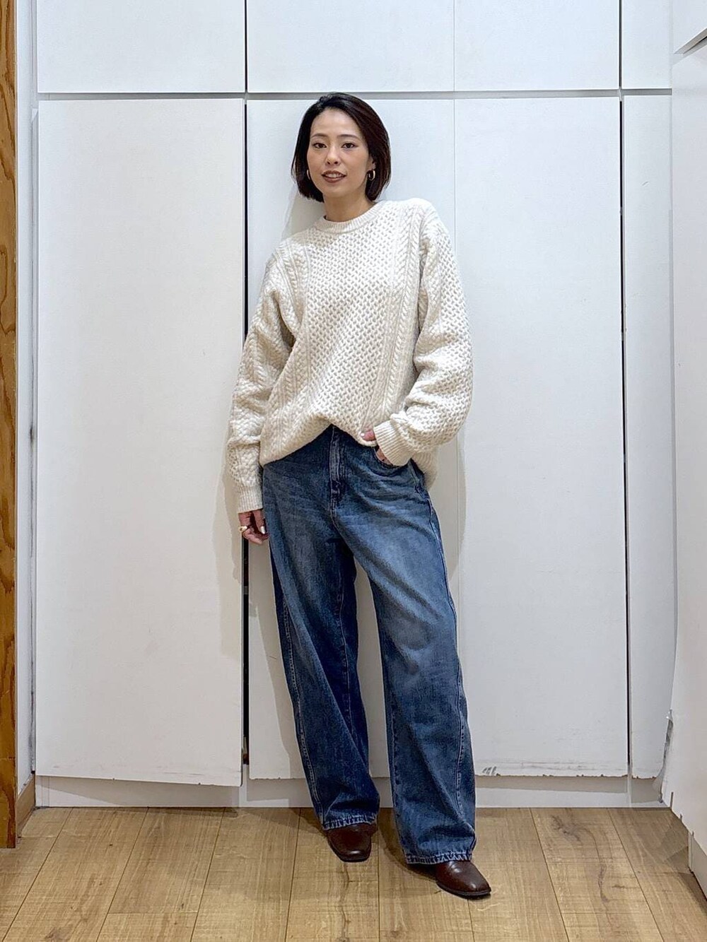 ブラウン系のブーツ、ホワイト系のニット/セーター、ブルー系のデニムパンツを着用したレディースの冬コーディネートの3枚目の写真