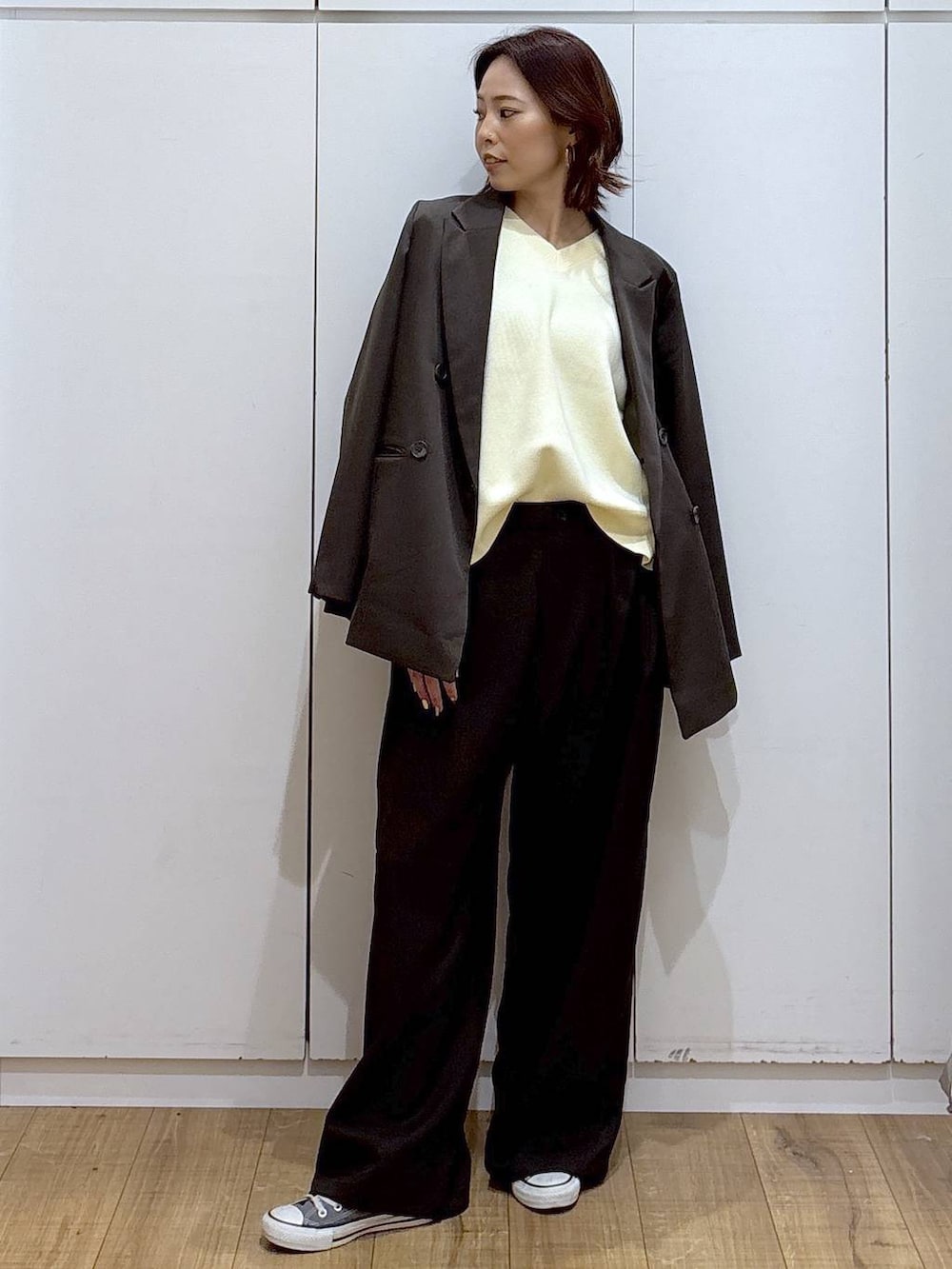 イエロー系のニット/セーター、ブラウン系のテーラードジャケット、ブラウン系のその他パンツを着用したレディースの春コーディネートの2枚目の写真