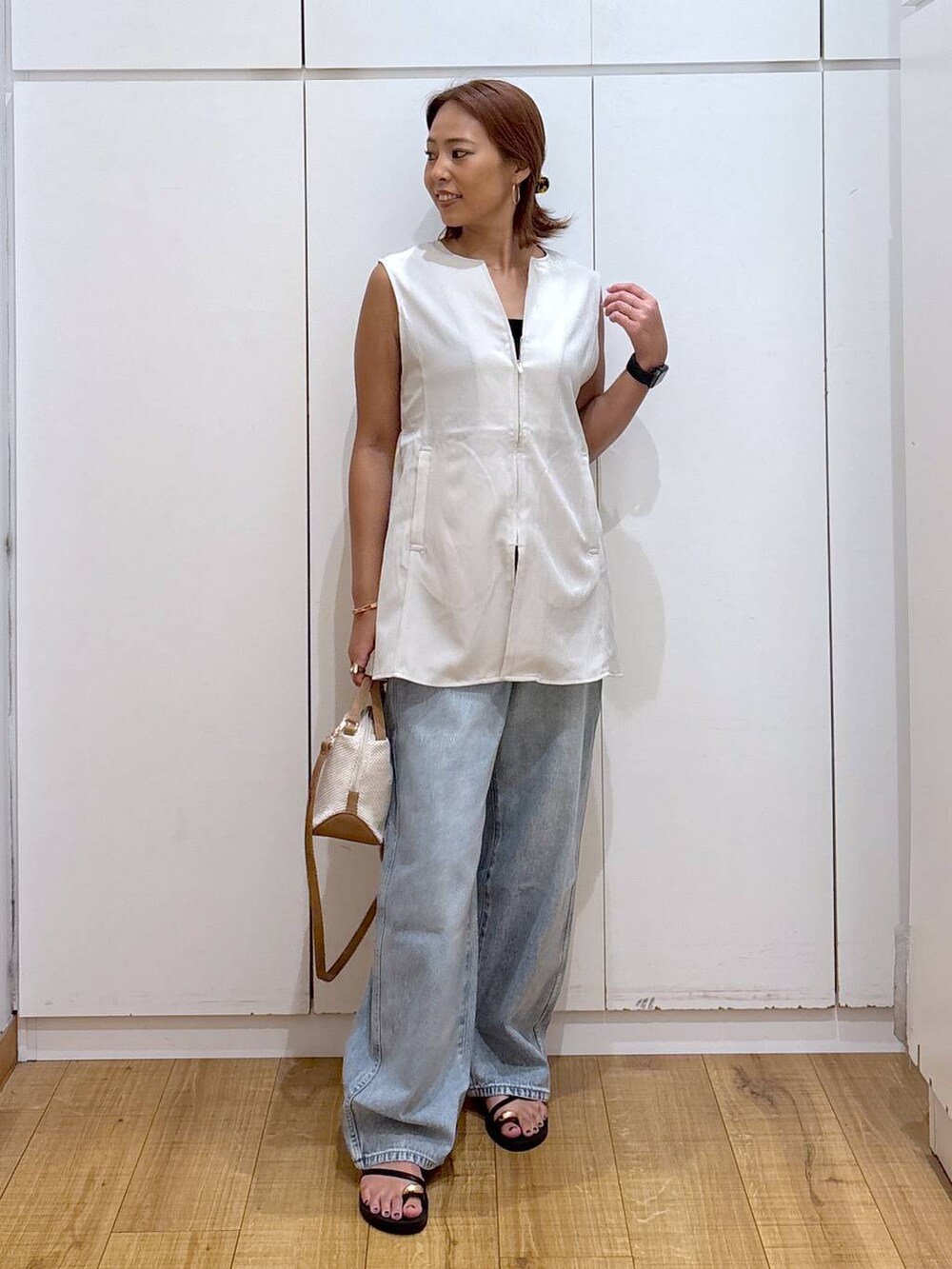 ブルー系のデニムパンツ、ホワイト系のショルダーバッグ、ブラック系のキャミソールを着用したレディースの夏コーディネートの4枚目の写真