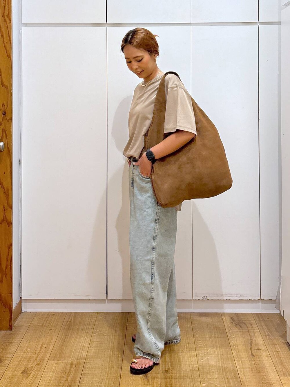 ブラウン系のサンダル、ベージュ系のTシャツ/カットソー、ブルー系のデニムパンツを着用したレディースの秋コーディネートの4枚目の写真