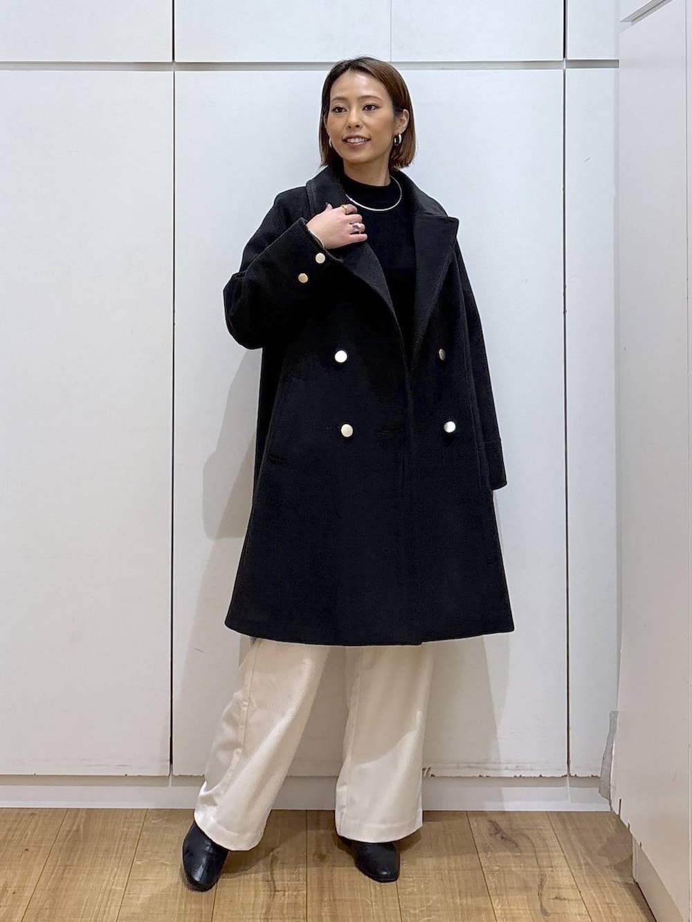 ブラック系のチェスターコート、ブラック系のニット/セーター、グレー系のその他パンツを着用したレディースの秋コーディネートの2枚目の写真