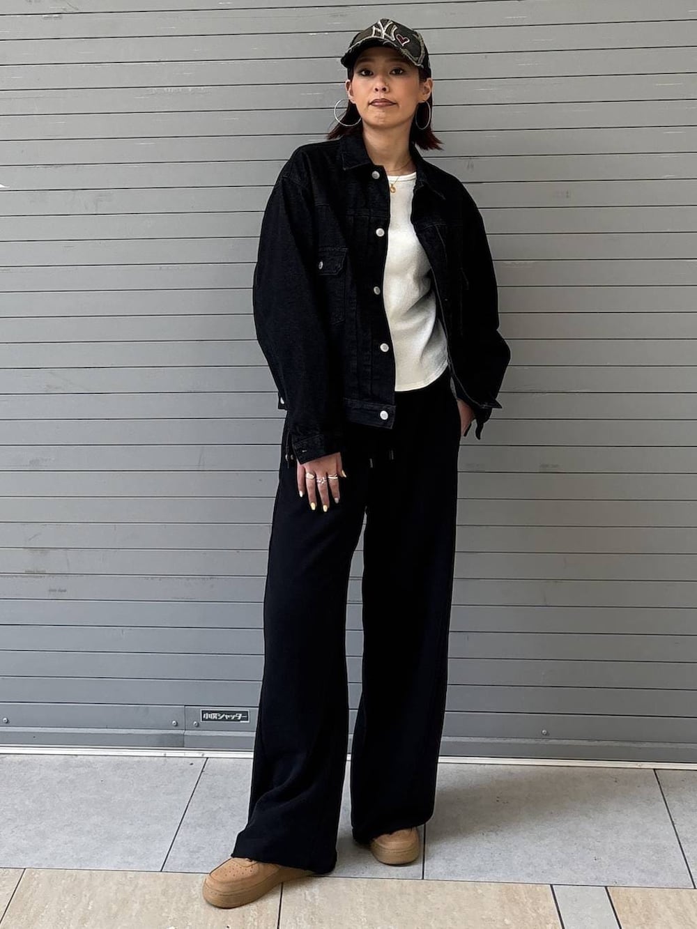 ブラック系のデニムジャケット、ブラック系のスウェットパンツ、ゴールド系のネックレスを着用したレディースの春コーディネートの3枚目の写真