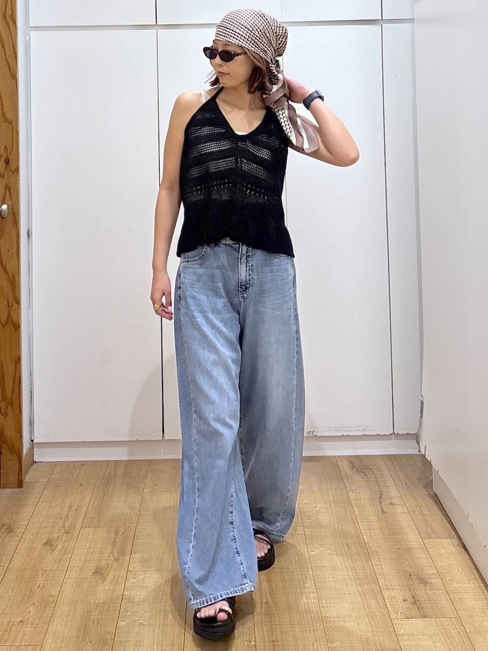 ホワイト系のキャミソール、ブルー系のデニムパンツ、ブラック系のサンダルを着用したレディースの春コーディネートの6枚目の写真