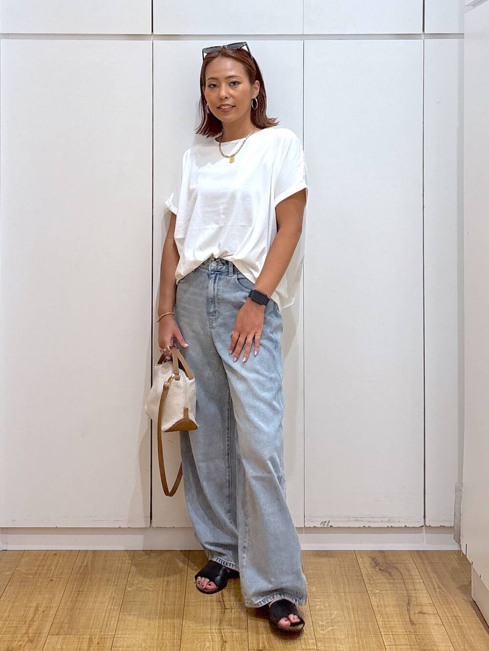 ブルー系のデニムパンツ、ホワイト系のショルダーバッグ、ホワイト系のTシャツ/カットソーを着用したレディースの夏コーディネートの3枚目の写真