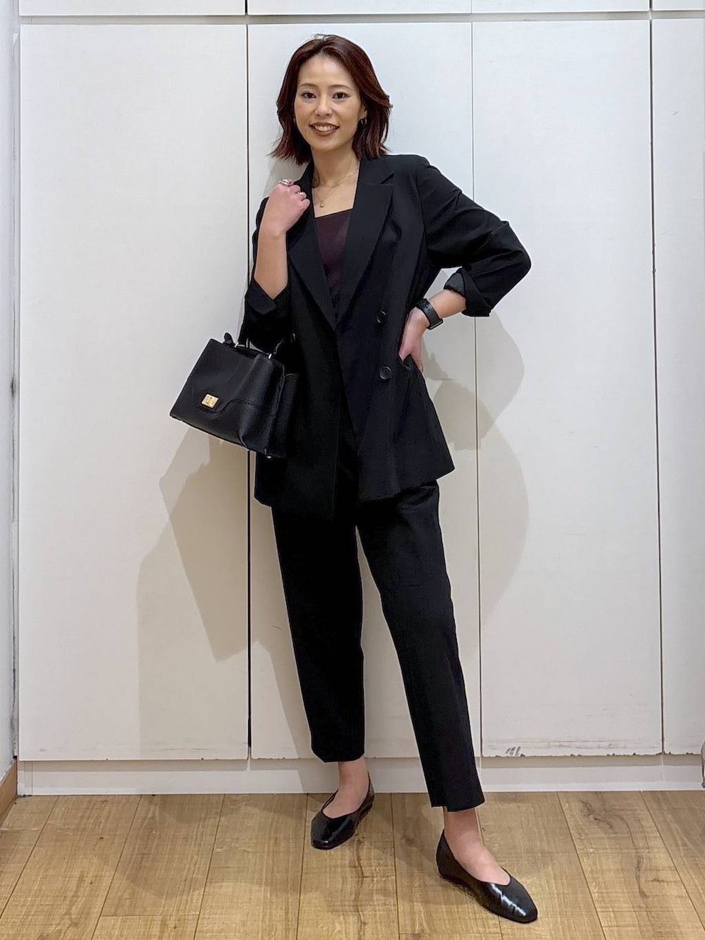 ブラック系のパンプス、ブラック系のスラックス、ブラック系のテーラードジャケットを着用したレディースの春コーディネートの2枚目の写真