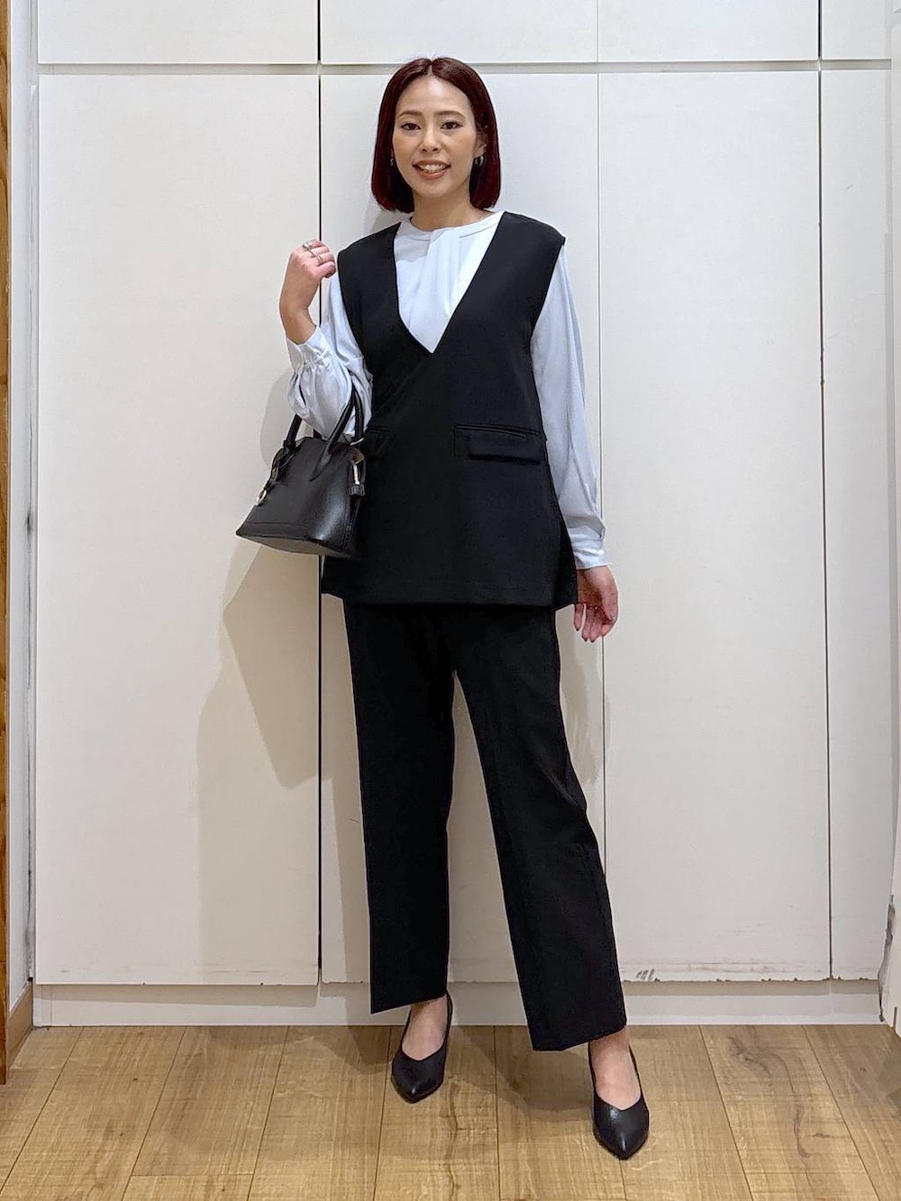 ブラック系のショルダーバッグ、ブラック系のパンプス、ブルー系のシャツ/ブラウスを着用したレディースの春コーディネートの2枚目の写真