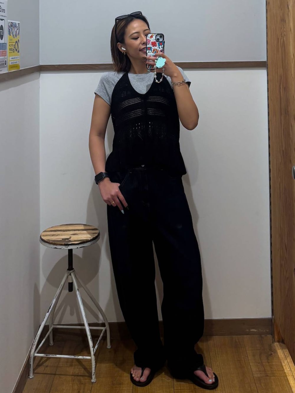 ブルー系のデニムパンツ、ブラック系のサンダル、ブラック系のベストを着用したレディースの春コーディネートの2枚目の写真