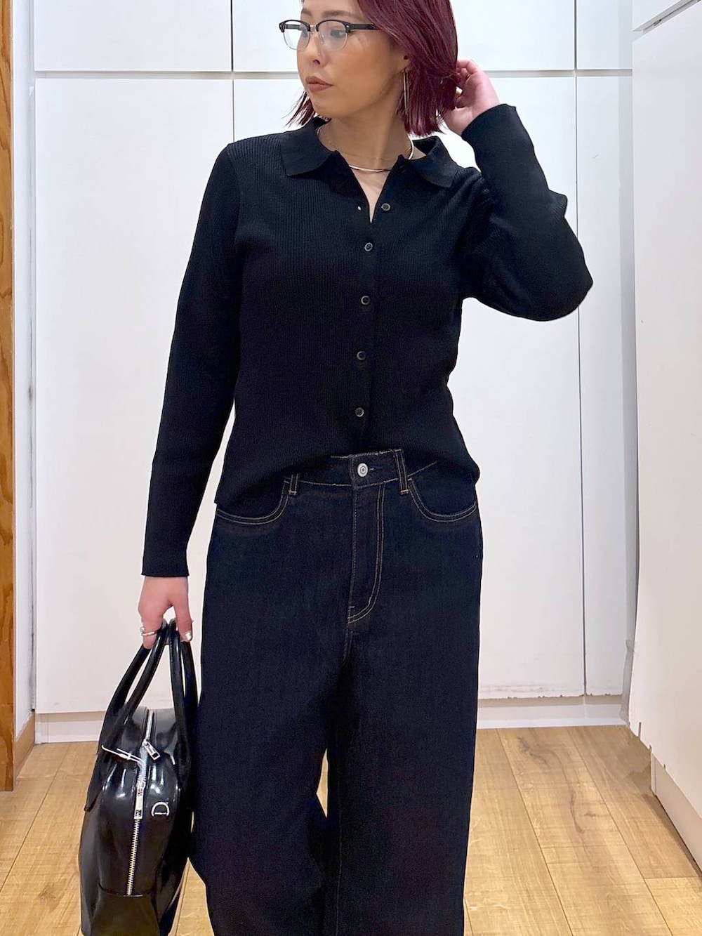 ブルー系のデニムパンツ、ブラック系のボストンバッグ、ブラック系のカーディガン/ボレロを着用したレディースの春コーディネートの6枚目の写真