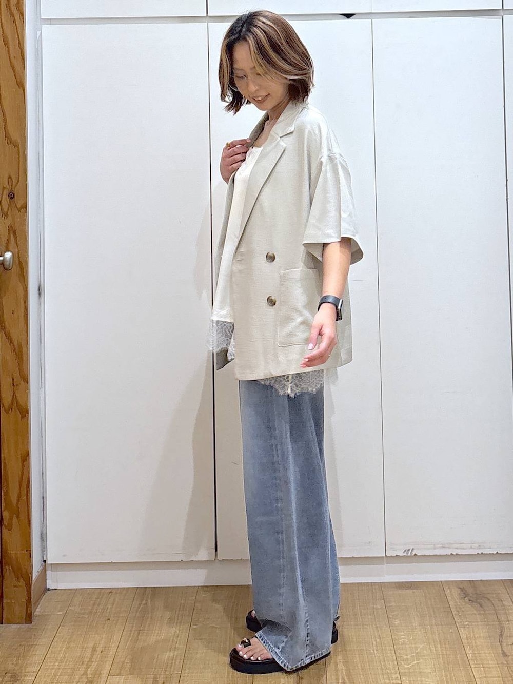 ホワイト系のキャミソール、ブルー系のデニムパンツ、ベージュ系のテーラードジャケットを着用したレディースの春コーディネートの4枚目の写真