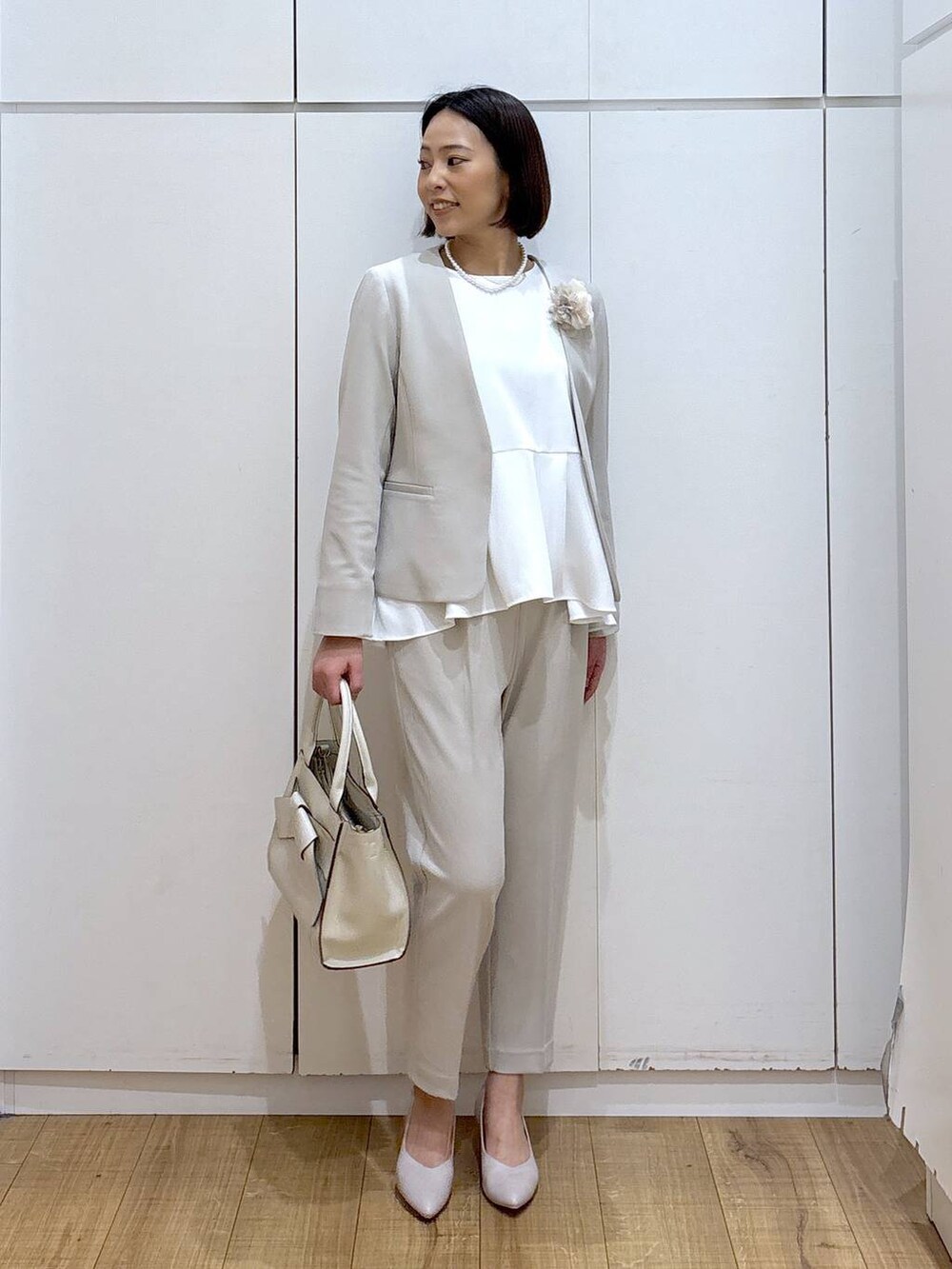 ホワイト系のパンプス、ベージュ系のセットアップ、ベージュ系のハンドバッグを着用したレディースの冬コーディネートの5枚目の写真