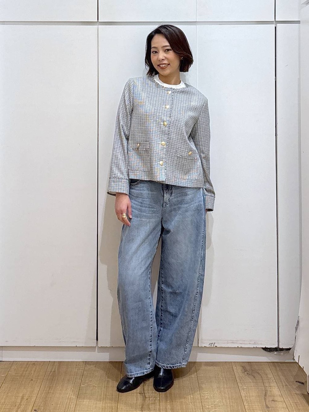 ブラック系のセットアップ、ホワイト系のテーラードジャケット、ブラック系のブーツを着用したレディースの冬コーディネートの3枚目の写真