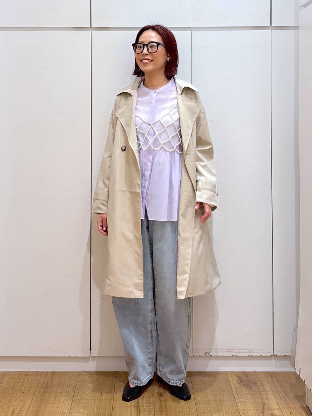 ホワイト系のベスト、ブルー系のデニムパンツ、ベージュ系のトレンチコートを着用したレディースの春コーディネートの2枚目の写真