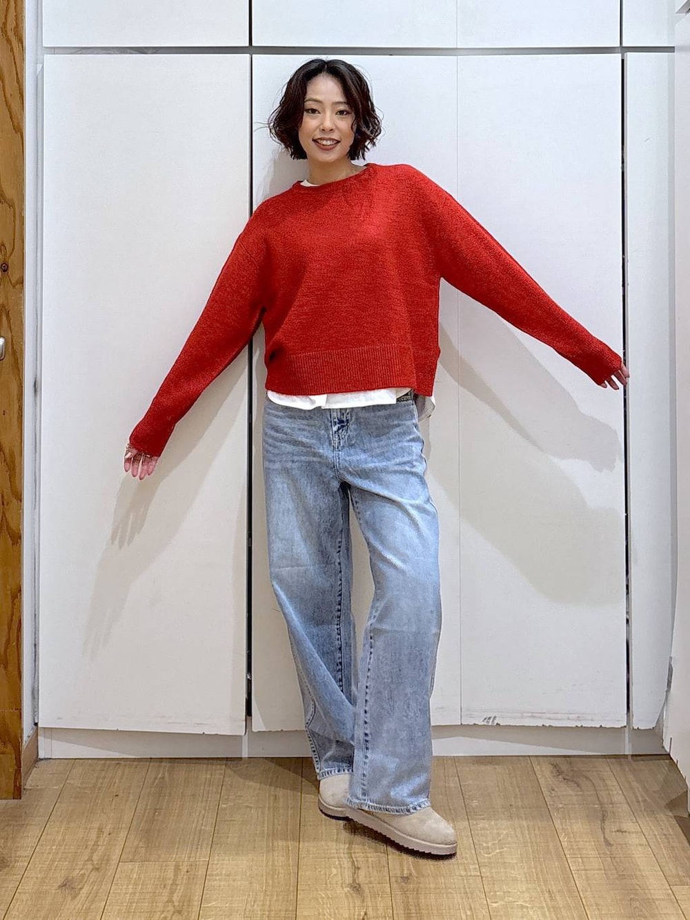 ブルー系のデニムパンツ、レッド系のニット/セーター、ホワイト系のTシャツ/カットソーを着用したレディースの冬コーディネートの3枚目の写真