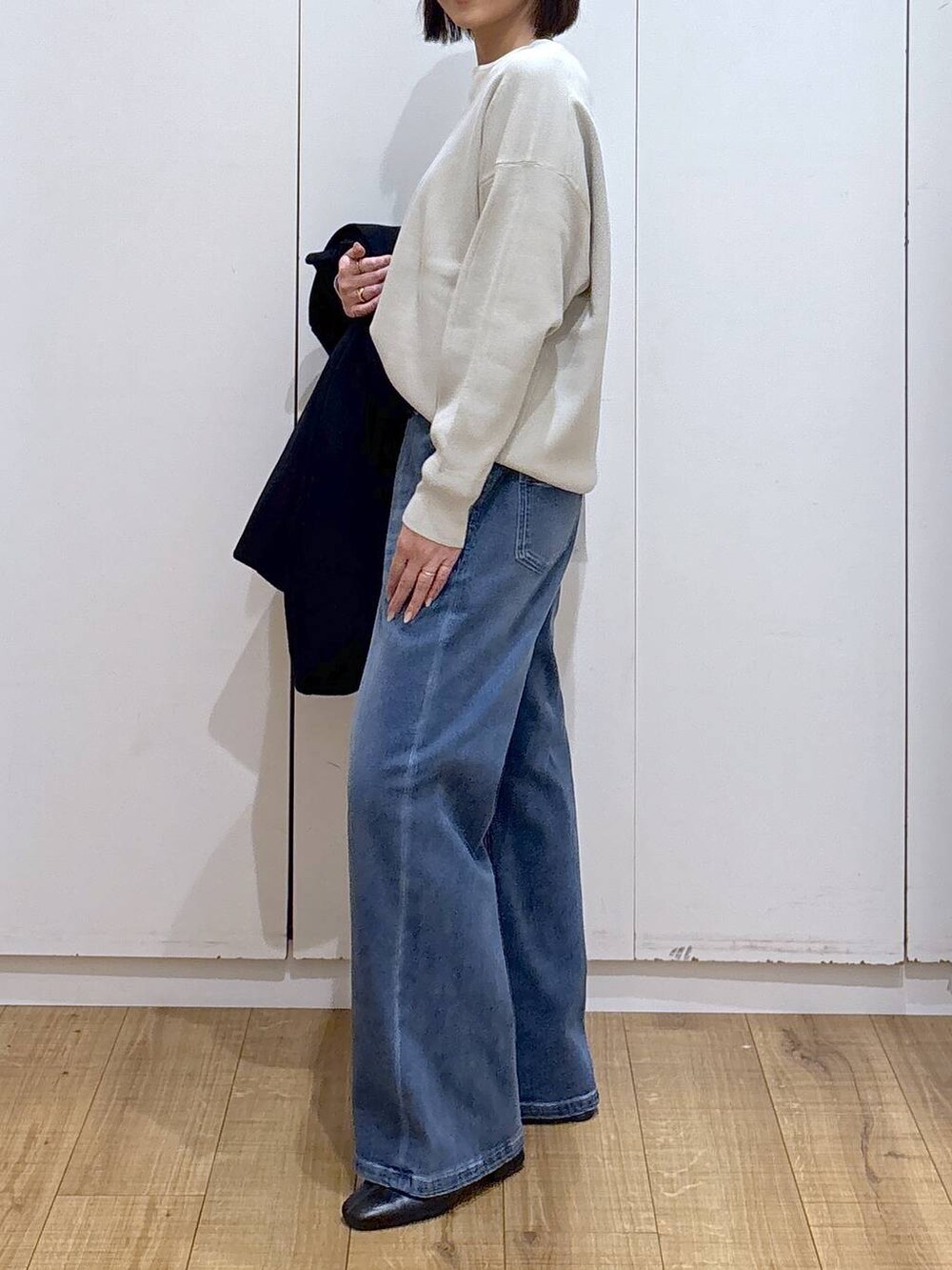 ブルー系のチェスターコート、ベージュ系のスウェット、ブラック系のブーツを着用したレディースの秋コーディネートの6枚目の写真