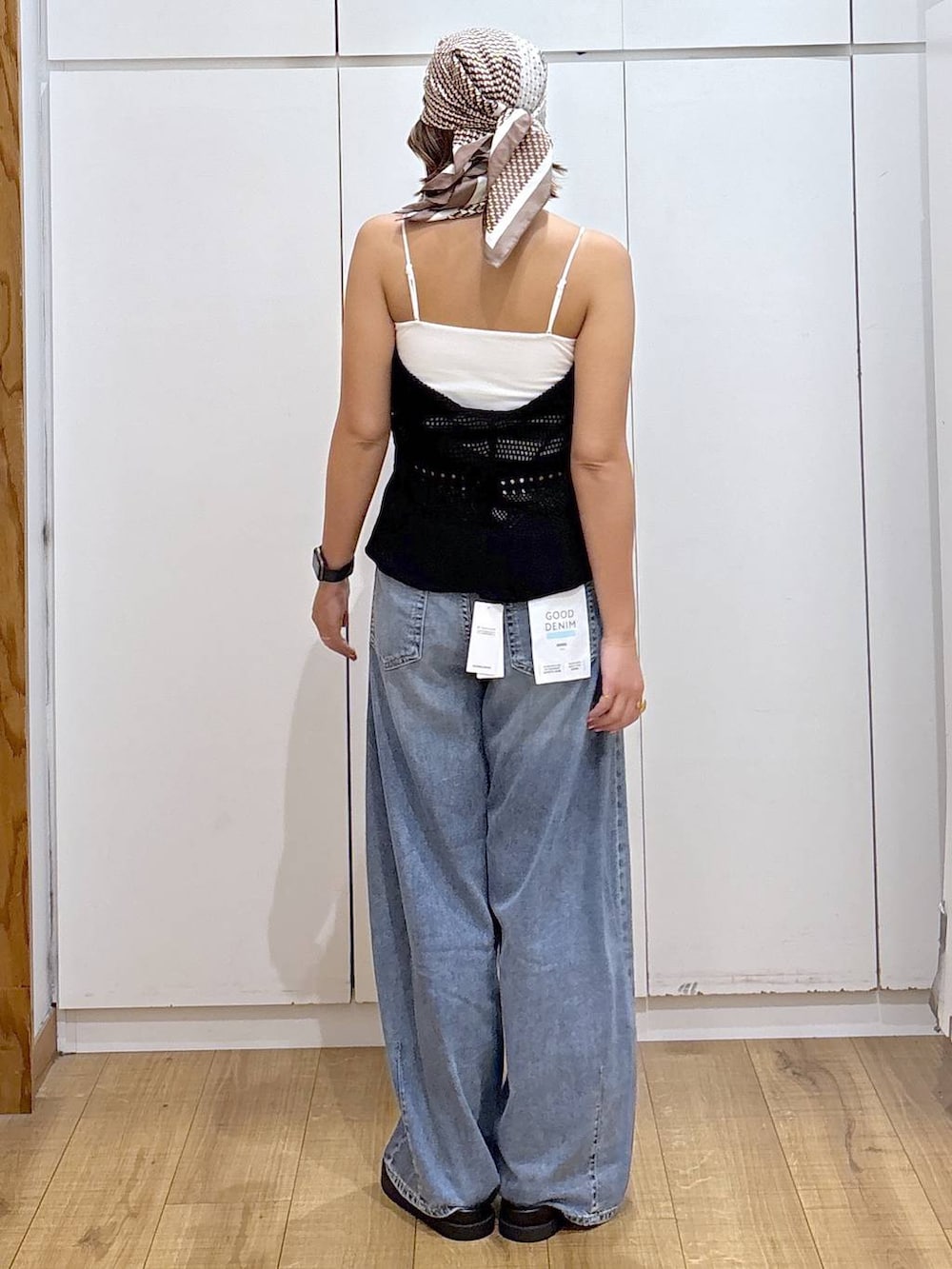 ホワイト系のキャミソール、ブルー系のデニムパンツ、ブラック系のサンダルを着用したレディースの春コーディネートの4枚目の写真