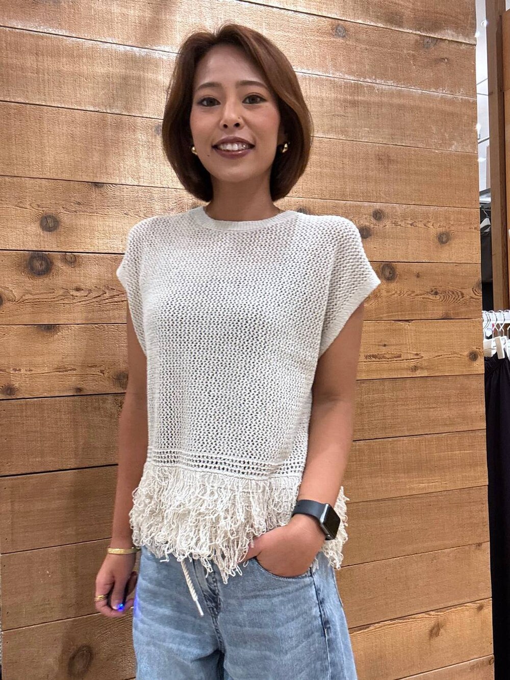 ベージュ系のベスト、ブルー系のデニムパンツを着用したレディースの夏コーディネートの5枚目の写真
