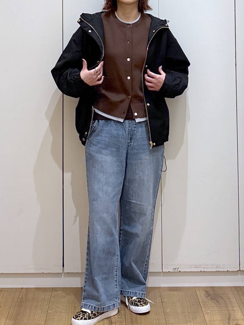 ブルー系のデニムパンツ、ブラック系のマウンテンパーカー、ブラウン系のカーディガン/ボレロを着用したレディースの春コーディネートの2枚目の写真