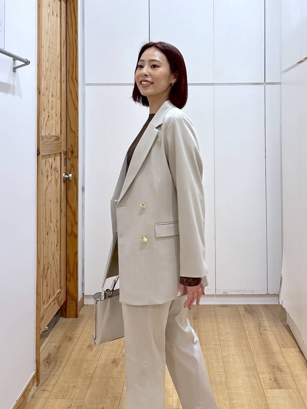 ベージュ系のスラックス、ベージュ系のテーラードジャケット、ベージュ系のショルダーバッグを着用したレディースの春コーディネートの6枚目の写真