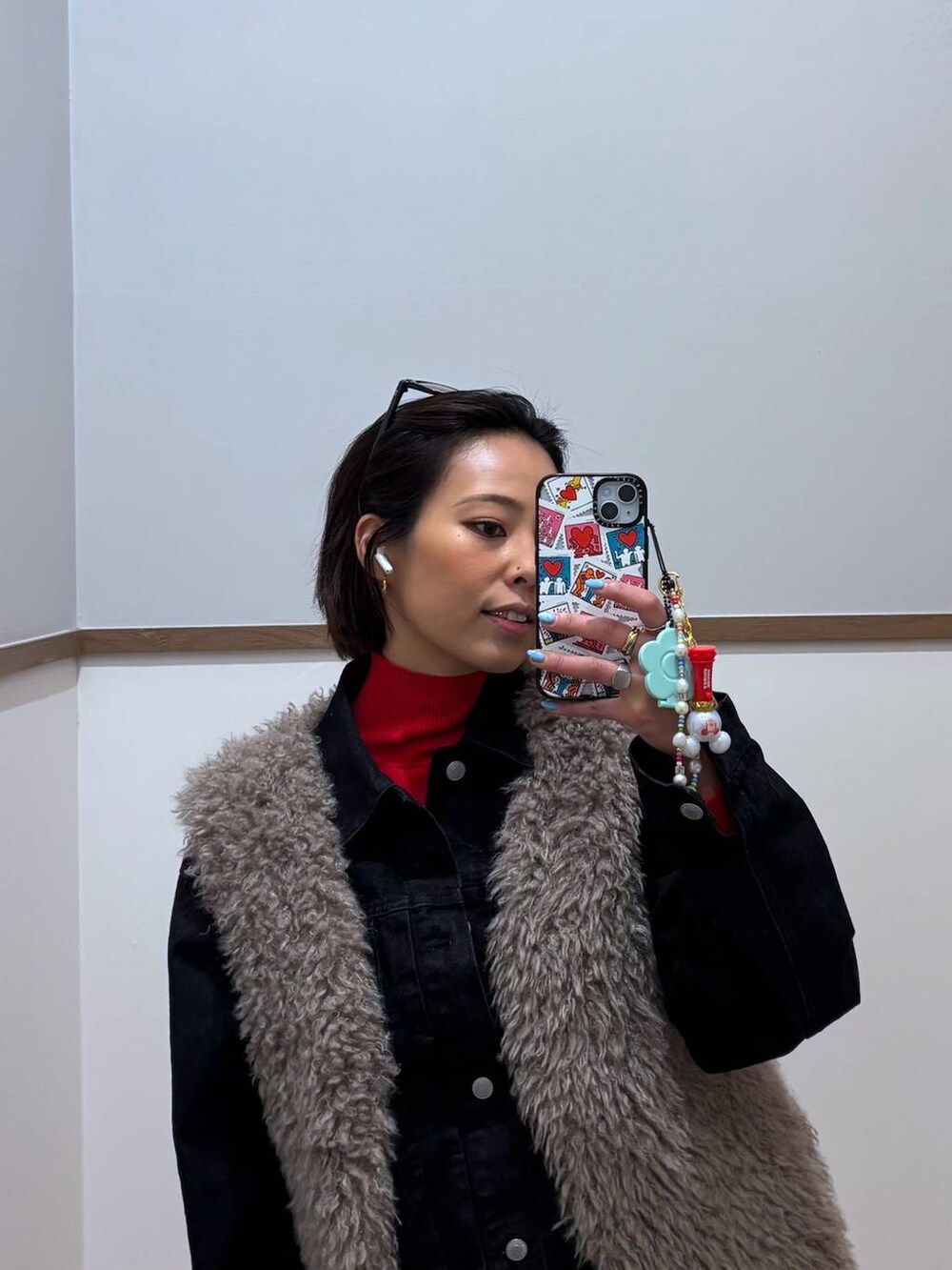 レッド系のニット/セーター、ブラック系のデニムジャケット、ゴールド系のピアス(両耳用)を着用したレディースの冬コーディネートの5枚目の写真