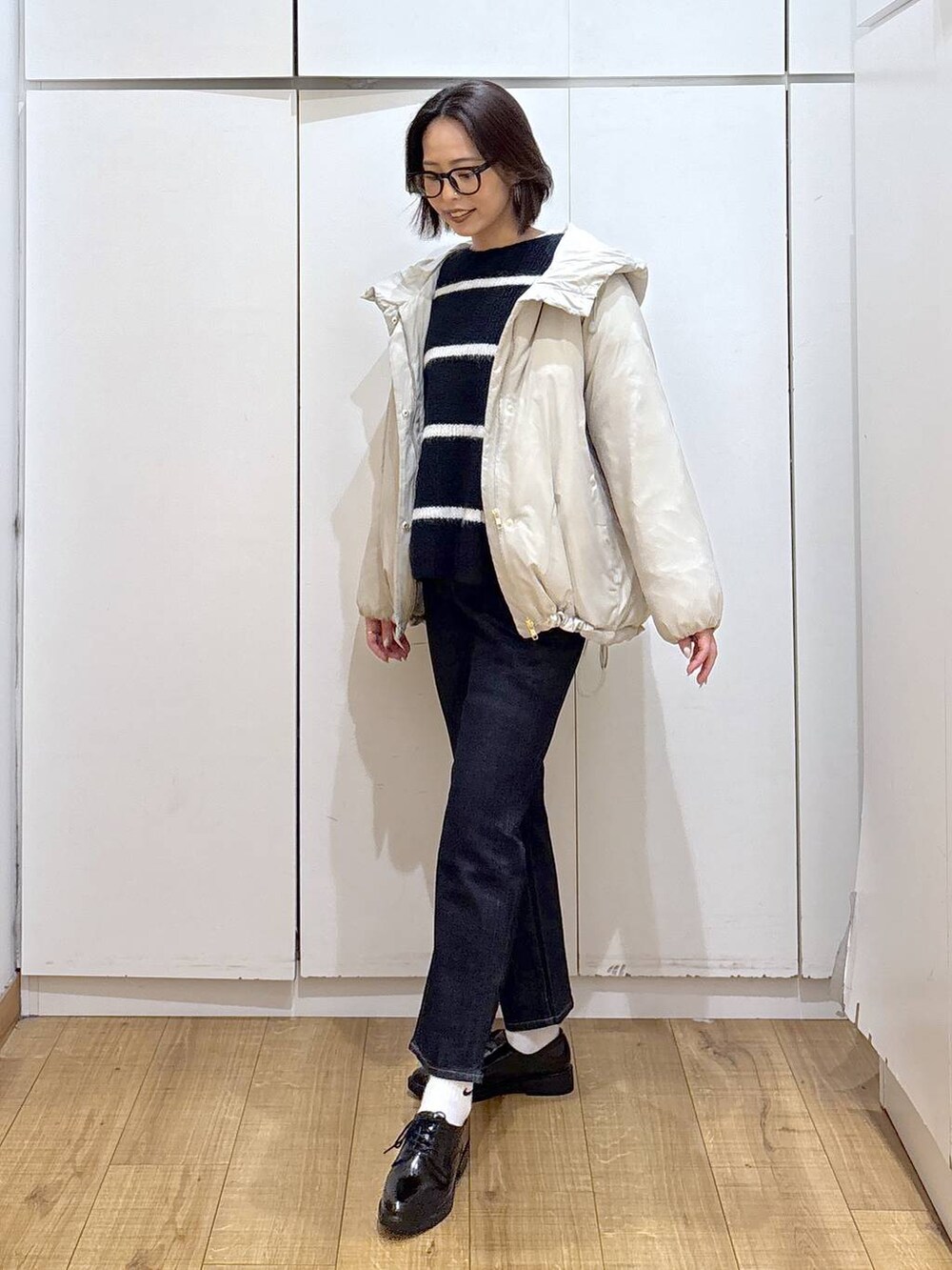 ベージュ系のダウンジャケット/コート、ブルー系のデニムパンツ、ブルー系のニット/セーターを着用したレディースの秋コーディネートの3枚目の写真