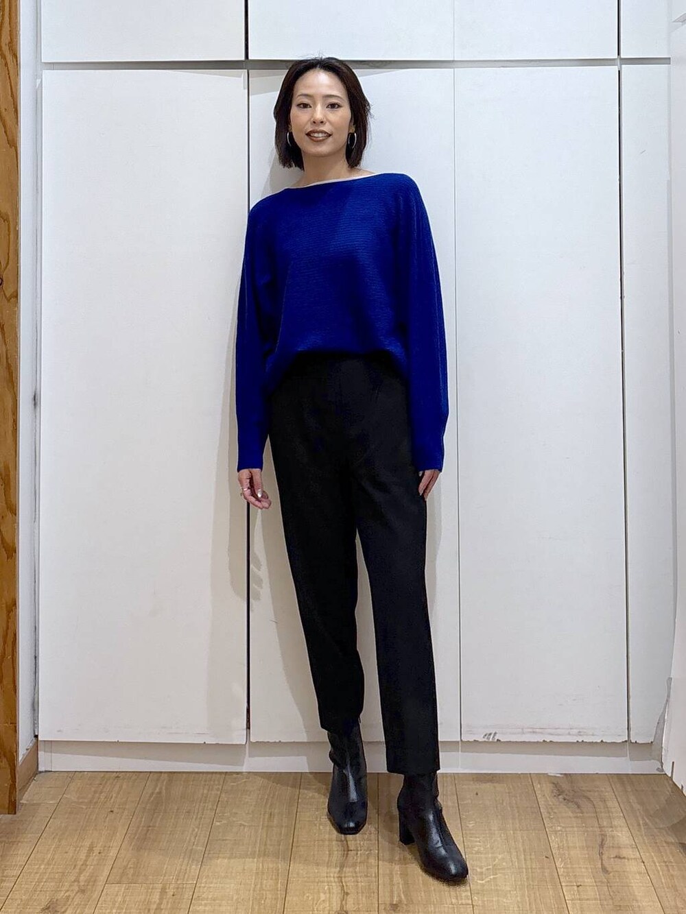 ブラック系のその他パンツ、ブルー系のニット/セーター、ブラック系のブーツを着用したレディースの秋コーディネートの2枚目の写真